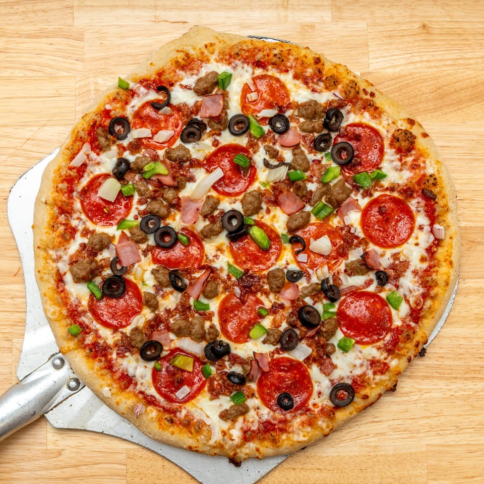 A freshly baked My Guy Craftin' Brews pizza, loaded with pepperoni, sausage, ham, olives, and peppers.